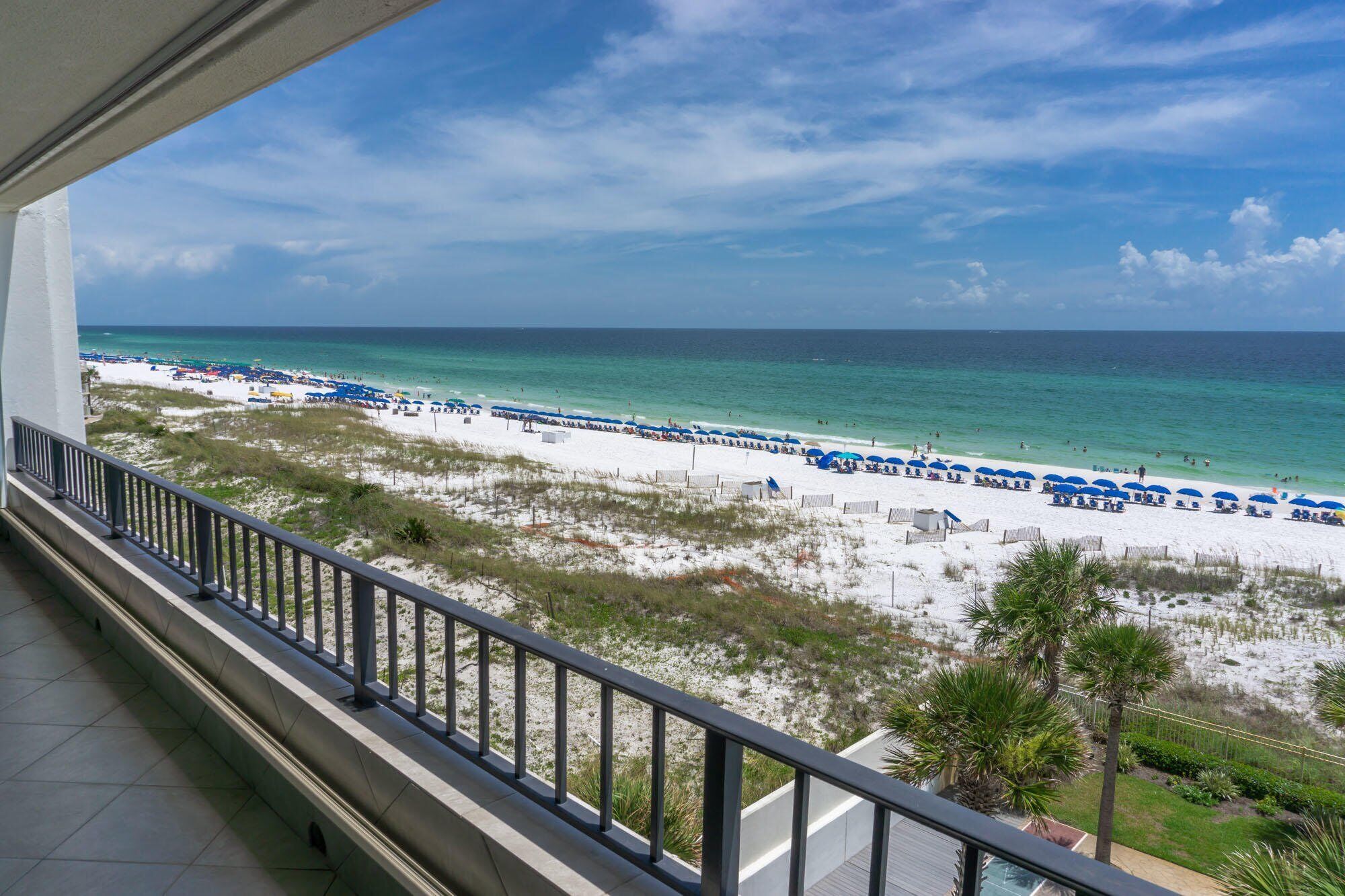 Blick auf einen Strand vom Balkon mit Geländer, mit Sandstrand und Meer.