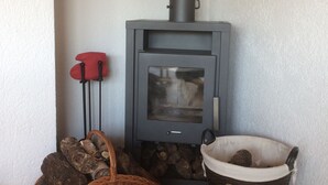 A wood-burning stove with logs and a basket of firewood.