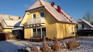 A yellow house with a red roof, a balcony, and a chimney.