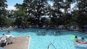 A swimming pool surrounded by trees and white lounge chairs. - Spectacular waterfront luxury (Village of Four Seasons)
