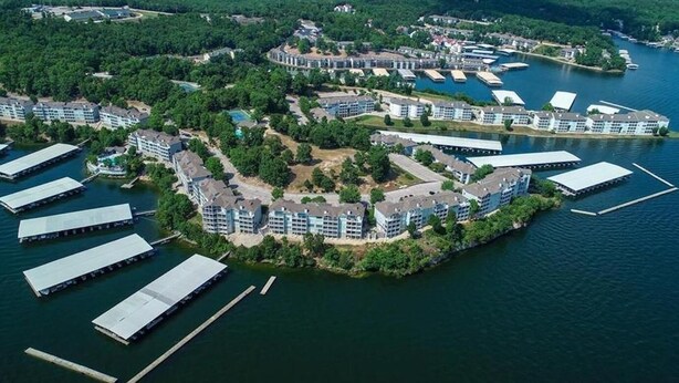 An aerial view of a waterfront hotel with multiple buildings, docks, and a lake. - Spectacular waterfront luxury (Village of Four Seasons)