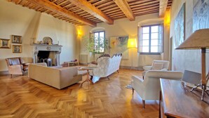 Uma sala de estar ampla com piso de madeira, lareira e uma grande janela.