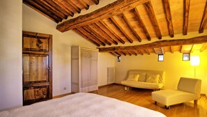 Quarto com teto de madeira, cama, sofá e guarda-roupa.