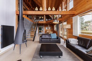 Cozy living area with a fireplace, sofa, and coffee table, featuring a staircase and large window with a view.