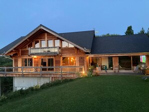 Situated on a serene grassy area, this cabin-style building features a spacious balcony and large windows.