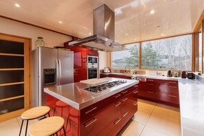 Enjoy cooking in this kitchen with a central island, oven, and stovetop, offering a view of the surrounding landscape.