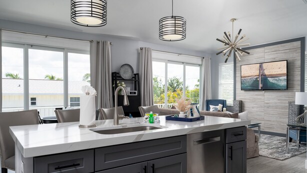 A modern kitchen with a large island, pendant lights, and a view of the outdoors. - Modern 4BR Beach House | Pool, Walk to Beach & Prime Location (Fort Myers Beach)