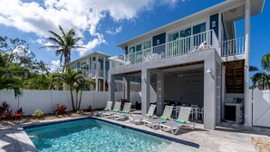 A two-story house with a swimming pool, outdoor seating, and a covered patio area. - Modern 4BR Beach House | Pool, Walk to Beach & Prime Location (Fort Myers Beach)