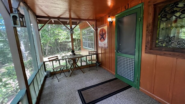 A wooden interior with a green door, a welcome sign, and a view of the outdoors. - Cardinal's Landing-Covered Porch - Pet-Friendly - Private-4WD-AWD (Bryson City)