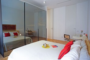 A hotel room with a large bed, a desk, a chair, and a small table with a vase. - Maison Art Gallery, just a few steps from the Duomo! (Milano)