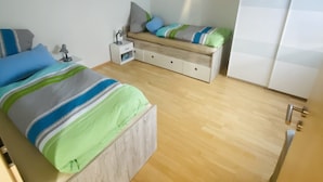 Un dormitorio con cama, mesita de noche, lámpara y armario.