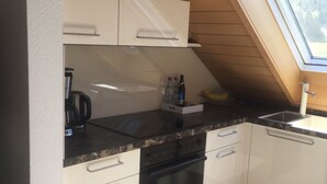 Eine kleine Küche mit weißen Schränken, einer schwarzen Arbeitsplatte und einem eingebauten Backofen.