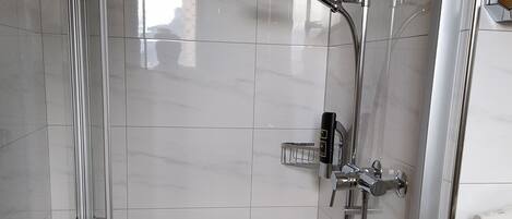 Un baño moderno con cabina de ducha de vidrio, ducha con cabezal de mano y grifo empotrado en la pared.