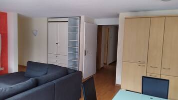 Una habitación con un sofá gris, un armario blanco con puerta de vidrio, un aparador de madera y una mesa de vidrio.