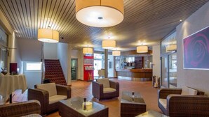 A lobby with wicker furniture, a staircase, and a reception area. - Hotel Sherlock Holmes "nur 200 m zur Gondelbahn Hasliberg" (Meiringen)