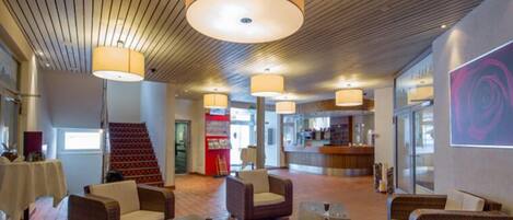 A lobby with wicker furniture, a staircase, and a reception area.