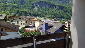 A balcony with a view of a town and mountains. - Hotel Sherlock Holmes "nur 200 m zur Gondelbahn Hasliberg" (Meiringen)