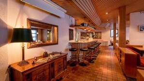 A bar area with a long counter, stools, and a mirror. - Hotel Sherlock Holmes "nur 200 m zur Gondelbahn Hasliberg" (Meiringen)