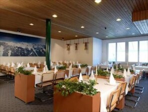 A conference room with tables set for a meeting, a large painting on the wall, and a wooden ceiling. - Hotel Sherlock Holmes "nur 200 m zur Gondelbahn Hasliberg" (Meiringen)