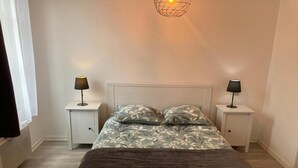 Une chambre à coucher comprenant un lit, deux tables de chevet et un luminaire fixé au mur.