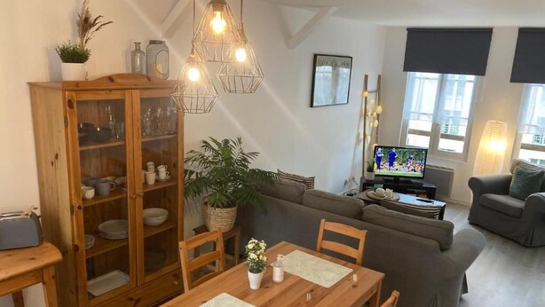 Un salon avec une table à manger en bois, un canapé et un téléviseur.