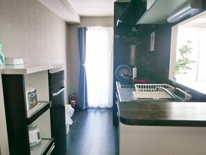 A compact kitchen with a stove, oven, and sink. A fire extinguisher is mounted on the wall.