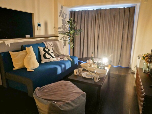 A modern living room with a blue sofa, a coffee table, and a TV mounted on the wall.