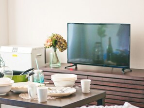 A dining table with various dishes, a vase with flowers, and a television in the background.