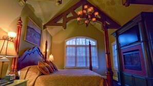 A bedroom with a large bed, a chandelier, a fireplace, and a window with blinds. - Lakefront Exclusive French Tudor Castle. 8400 sf. Nicest property on SML!  (Penhook)