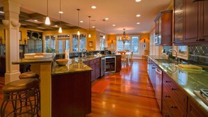 A spacious kitchen with wooden flooring, a central island, and pendant lighting. - Lakefront Exclusive French Tudor Castle. 8400 sf. Nicest property on SML!  (Penhook)
