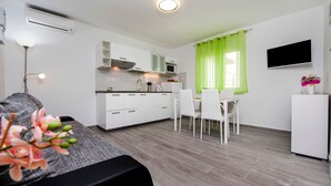 A modern kitchen with white cabinets, a microwave, and a sink. There is a dining area with a table and chairs.