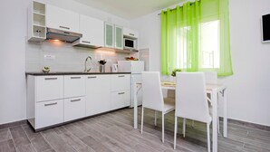 A modern kitchen with white cabinets, a microwave, and a dining area with a table and chairs.