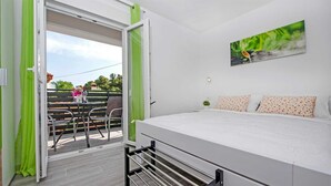 A bedroom with a bed, a painting, and a balcony with a table and chairs.