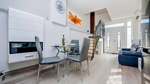 A modern living room with a dining area, a staircase, and a large window.