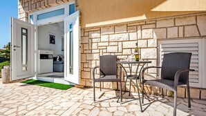 An open door leading to a modern kitchen with a dining area featuring wicker chairs and a table.