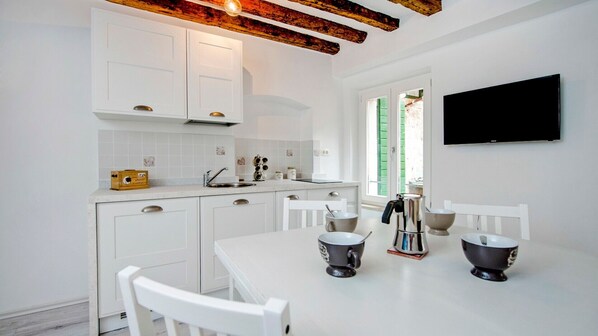 A modern kitchen with white cabinetry, a built-in oven, and a large window.