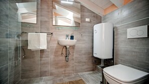 A modern bathroom with a glass shower enclosure, a white sink, and a Bosch water heater. - CA’ 3 VIE LAVANDA - One Bedroom Apartment (Rovinj)