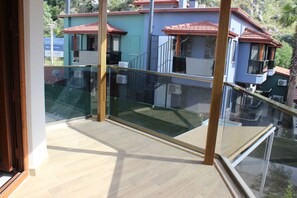 A balcony with a glass railing overlooking a residential area with houses and a signboard. - Iberia Villas (Ortaca)