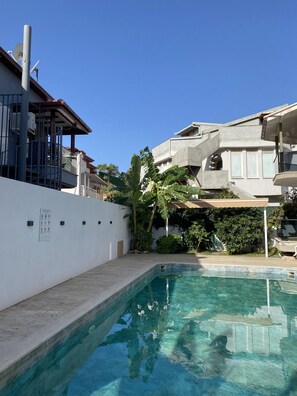 A swimming pool with a clear blue water, surrounded by a white wall and a concrete deck. - Iberia Villas (Ortaca)