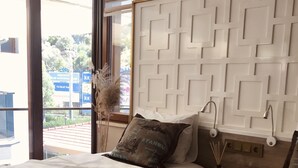 A hotel room with two beds, a view of the outside, and a decorative wall panel. - Iberia Villas (Ortaca)