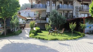 A multi-story building with balconies, a paved courtyard, and outdoor seating. - Iberia Villas (Ortaca)