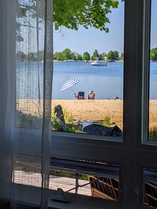 A view of a lake with boats, a sandy beach, and a chair with an American flag.