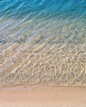 A clear view of a sandy beach with shallow water.