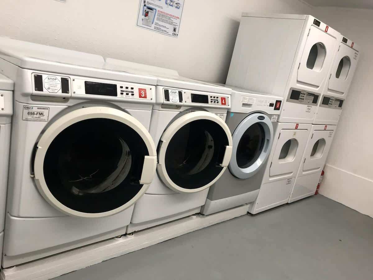 Une buanderie équipée de trois machines à laver à chargement frontal et d’un appareil de séchage superposé.