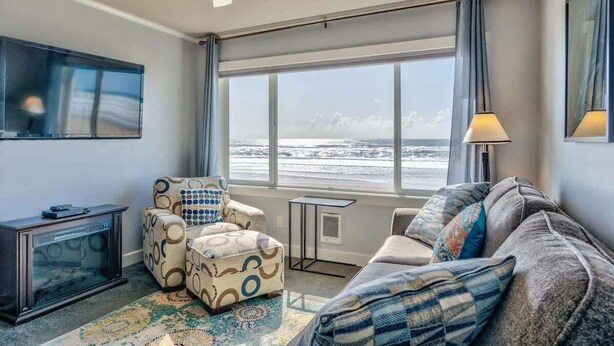Ein Wohnzimmer mit großem Fenster, Deckenventilator, Flachbildfernseher und Kamin.