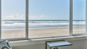 Ein Zimmer mit großem Fenster und Blick auf einen Strand.