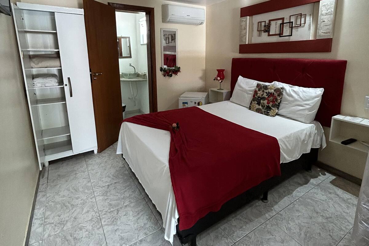 A bedroom with a bed, a wardrobe, a bedside table, and a nightstand.