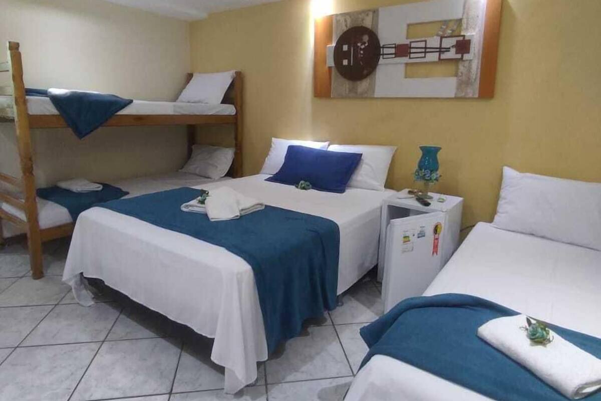 A hotel room with two single beds, a bunk bed, and a small bedside table with a lamp.
