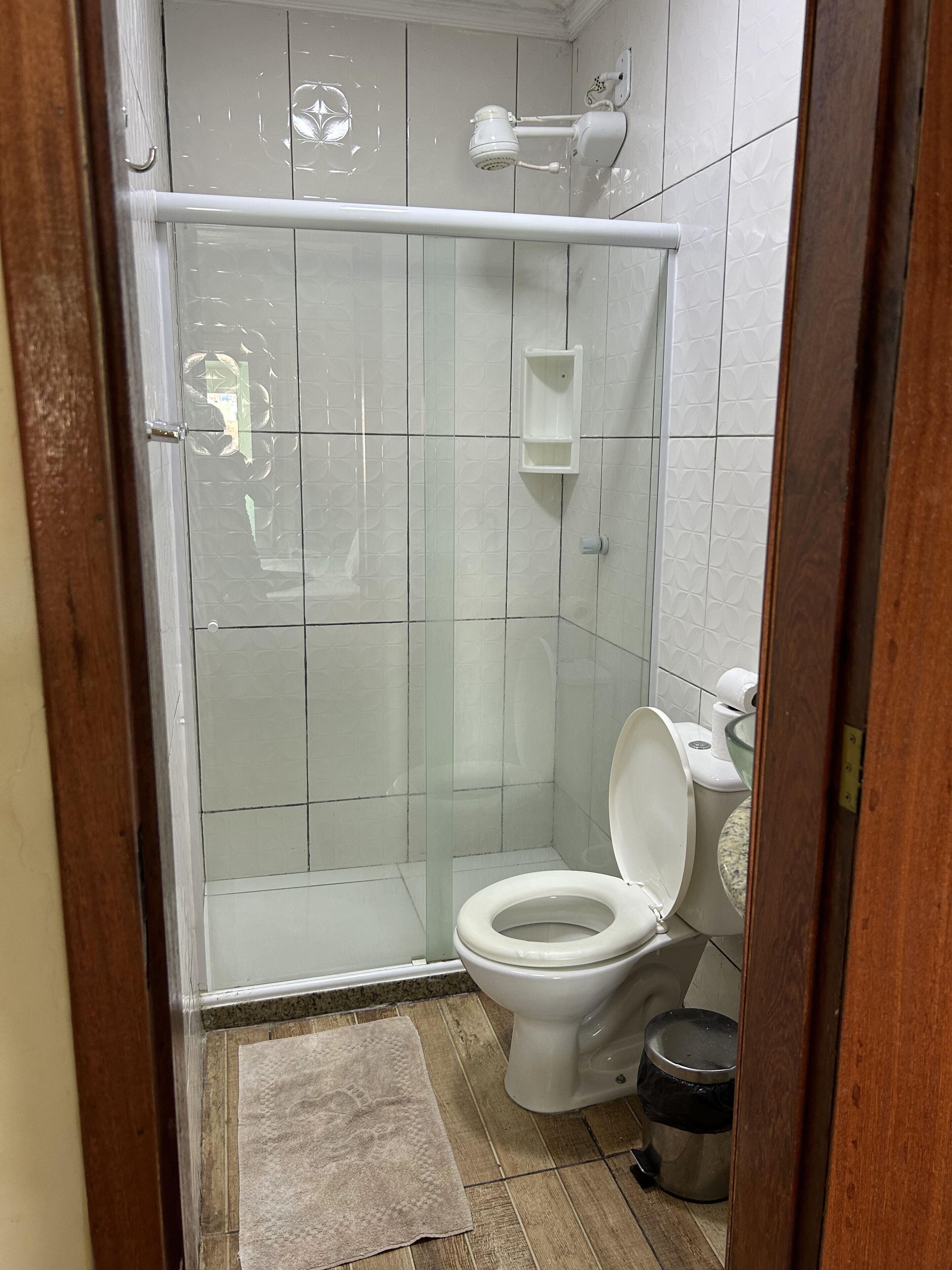 Ein Badezimmer mit Glasdusche, Toilette, Waschbecken und Mülleimer.