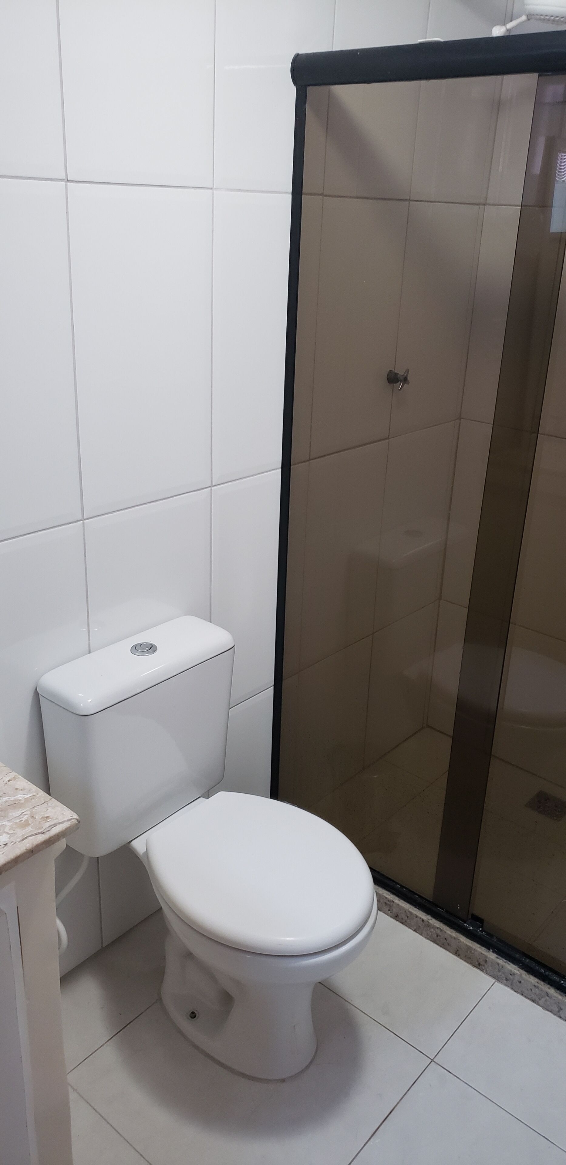 Un baño con inodoro, cabina de ducha y paredes de azulejos.